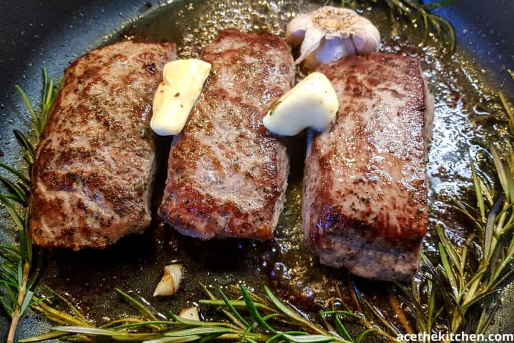 steak in a pan with butter garlic and rosemary